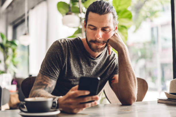 istock Handsome bearded hipster man use smartphone with coffee at table in cafe.Communication and technology concept 1217534580