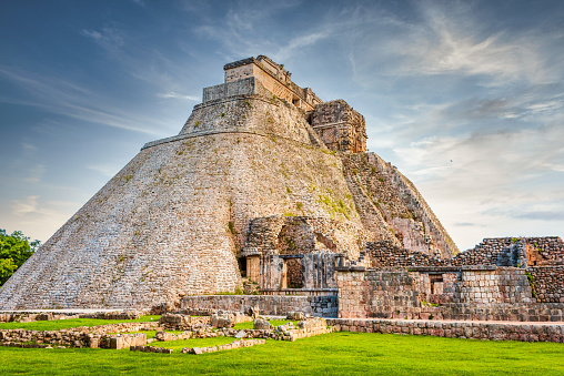 Pyramid of the Magician - Piramide del Adivino, central pyramid structure in the Maya Ruin Complex of Uxmal under blue summer sky. Pirámide del adivino is the tallest and most recognizable structure in Uxmal, Yucatan, Mexico, North America