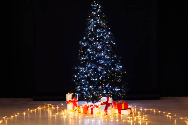 istock Christmas tree garland lights with New Year's gifts darkness 1217536143