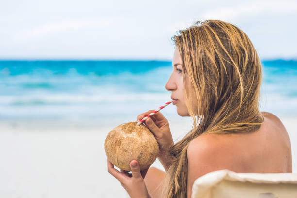 istock Young woman drinking coconut milk on Chaise-longue on beach. 1217536241