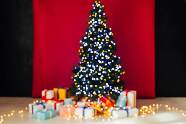 istock Christmas tree garland lights with new year's gifts red background 1217536887