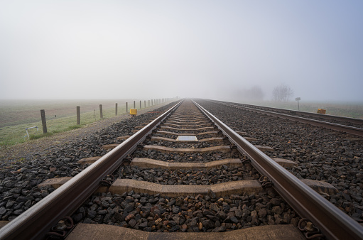 Empty railroad tracks disappearing into the dense, spring fog.
