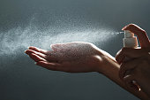 Close-up view of human hand and antiseptic spray bottle on dark background. Sanitation of hands. Control Epidemic Prevention measures of coronavirus