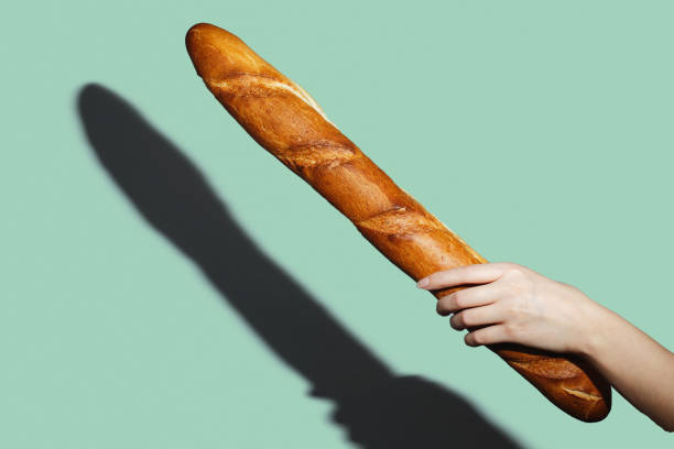 istock Female hands hold a bread loaf on green background. Flat lay, direct light 1217537345