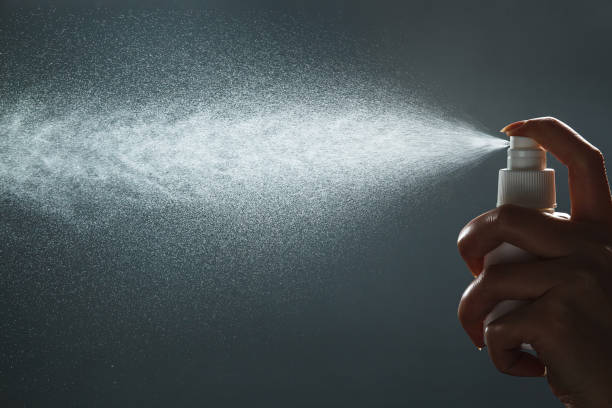 Close-up view of human hand and antiseptic spray bottle on dark background. Control Epidemic Prevention measures of coronavirus stock photo