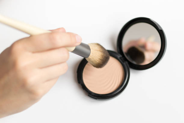 istock Hand holding a make up brush and highlighter with a little mirror 1217538813