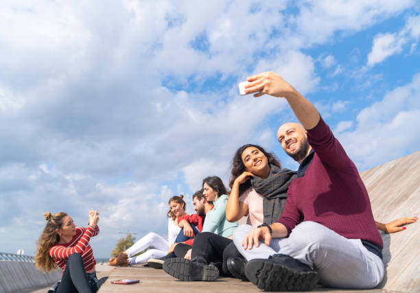 Group of cheerful friends using mobile phones and sharing