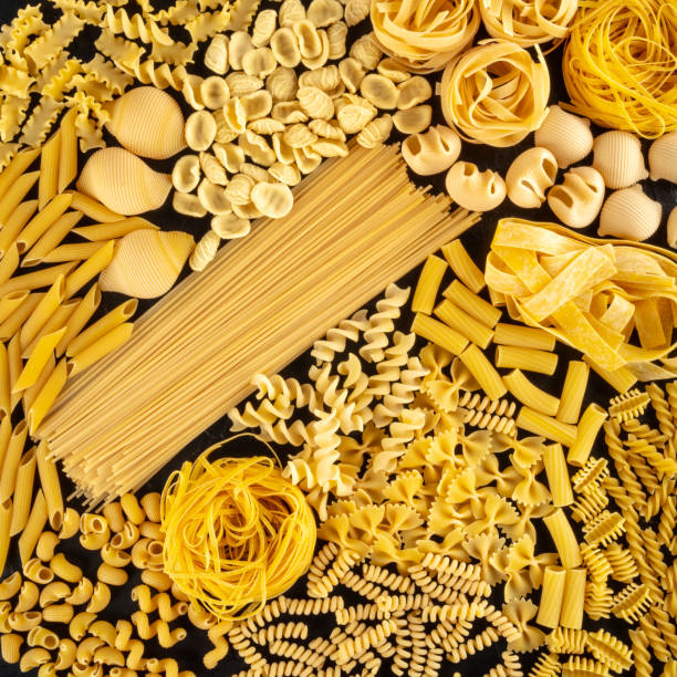 istock Italian pasta square background texture, a flat lay of many different pasta types, shot from the top on a black background 1217538971