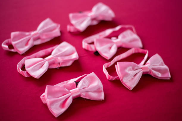 six pink coloured bow ties on top of red surface