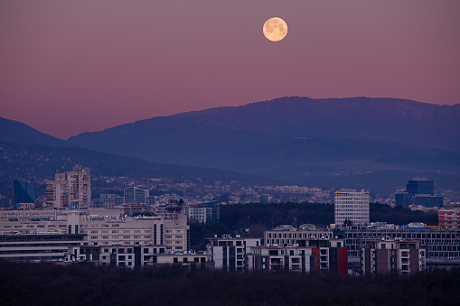 Super pink full moon setting down, just before sunset above the city of Sofia, Bulgaria , on 8th April 2020