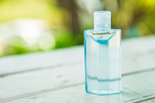 istock An alcohol bottle on white wooden table with green nature blurred background, 1217548775