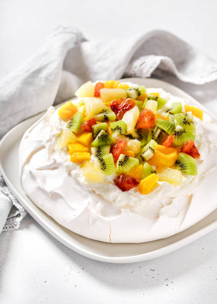 Delicious pavlova meringue cake with kiwi, mango, pineapple, blood orange slices and whipped cream. Delicious pavlova meringue cake with kiwi, mango, pineapple, blood orange slices and whipped cream. Selective focus. pavlova stock pictures, royalty-free photos & images