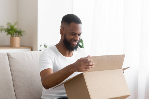 istock Online shopaholic. Glad african american man unpack parcel 1217551650