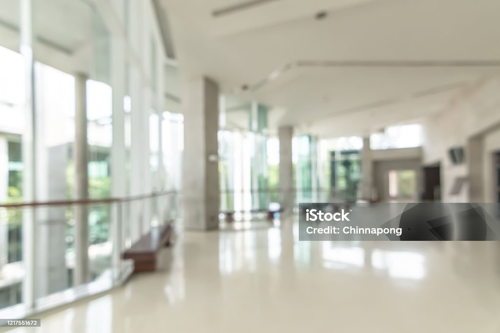 Hotel or office building lobby blur background interior view toward reception hall, modern luxury white room space with blurry corridor and building glass wall window Office Stock Photo