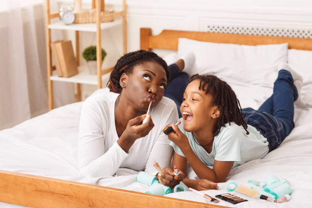 istock Little afro girl doing makeup with her mom in bed 1217552157