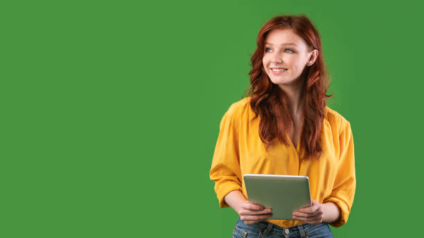 istock Smiling Girl Holding Digital Tablet Looking Aside On Green Background 1217552242
