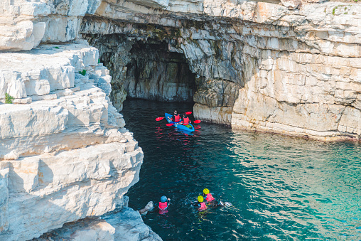 people swimming on kayaks and in water to grotto cave in sea famous landmark summer vacation