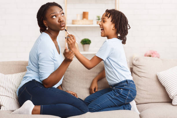 istock Happy african child doing makeup for her mommy 1217553035