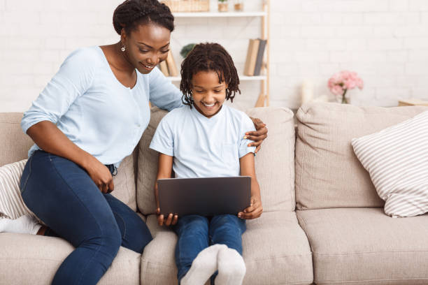 istock Afro mom and daughter using laptop on sofa 1217553194