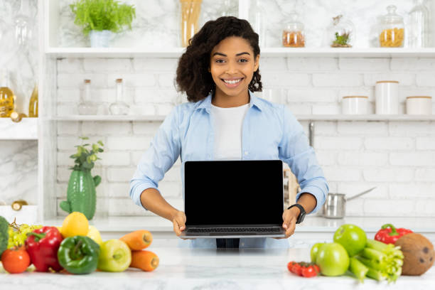 istock Afro girl holding laptop in the kitchen 1217553331