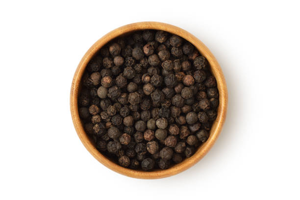istock Black pepper in wooden bowl on white background 1217555072