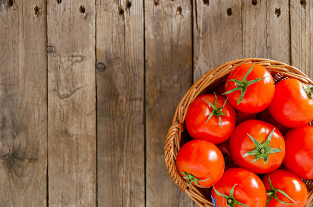 istock Wicker basket with tomatoes on an old wooden table. 1217557901
