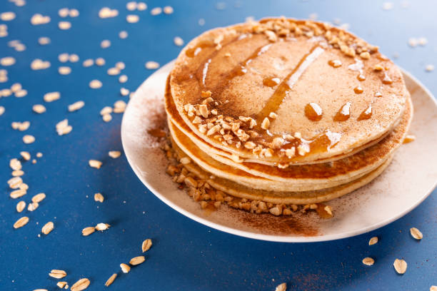 Oat pancakes on a white dish with nuts and syrup, with oatmeal. stock photo