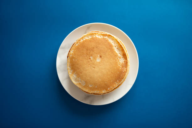 Fresh pancakes on a white dish. Classic blue background. 2020 stock photo
