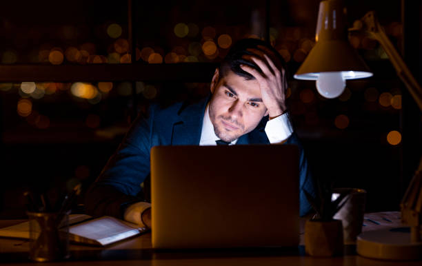 istock Thoughtful Businessman Looking At Laptop Sitting In Office At Night 1217558484