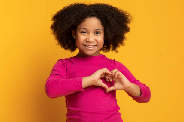 entzückende kleine afroamerikanische mädchen zeigt herz geste mit händen - heart shape child human hand childhood stock-fotos und bilder