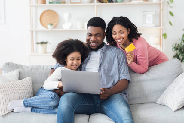 интернет-магазины. счастливая семья с помощью ноутбука и кредитной карты на дому - sale relationships loving indoors стоковые фото и изображения