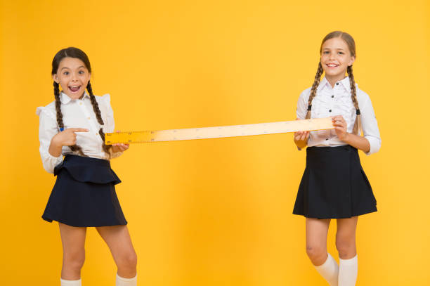istock Close or far. Measuring skills. Measuring distance. Measuring equipment. Kids students study math. Knowledge day. Schoolgirls school uniform hold big ruler. Geometry school lesson. Teamwork concept 1217559839