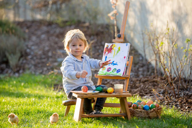 sweet toddler child, painting eggs in garden with little chicks running around him - baby chicken young bird young animal easter imagens e fotografias de stock