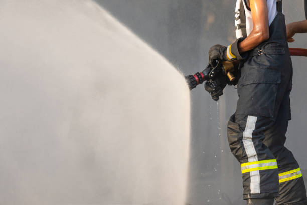 istock Firefighter spraying water from big water hose to prevent fire 1217561347