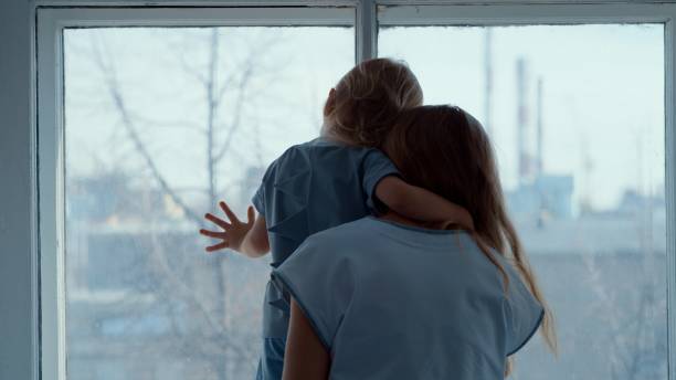 istock Mom with a small child look out the window 1217564325