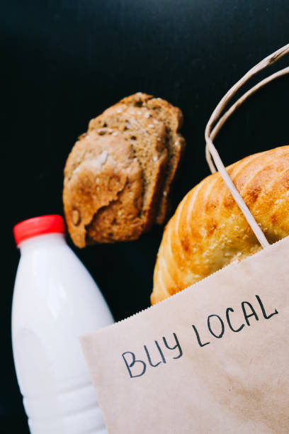 istock Buy local. milk and bread on a black table with a craft bag 1217564379