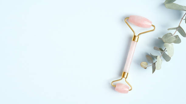 istock Rose quartz facial roller with eucalyptus leaf on blue background. Jade face massager, anti-aging, anti-wrinkle beauty skincare tool 1217564423