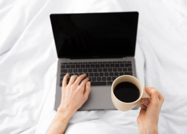 istock Hands typing on laptop in the morning on a white pillow bed 1217564503