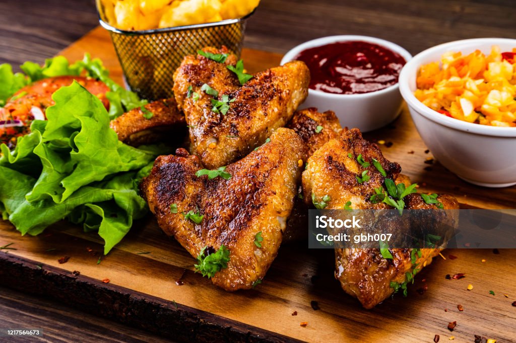 Barbecue chicken wings and vegetables on wooden board Chicken wings and vegetables on wooden table Animal Wing Stock Photo