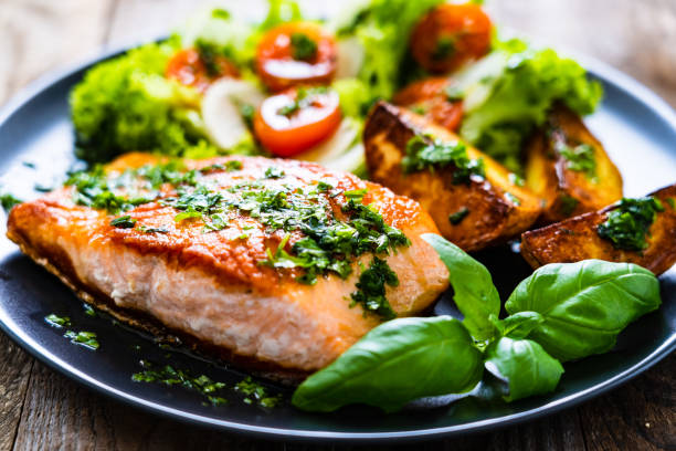 istock Fried salmon, fried potatoes and vegetables on wooden background 1217564756