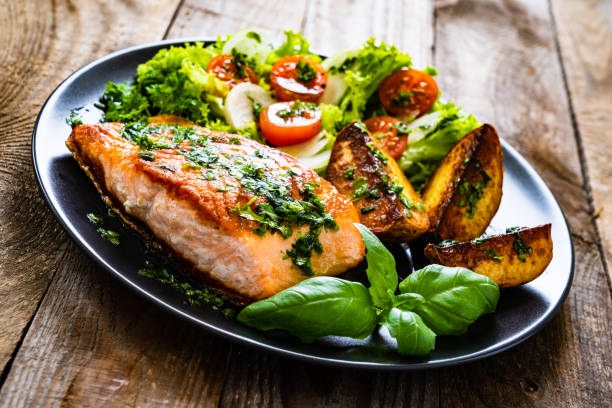 istock Fried salmon, fried potatoes and vegetables on wooden background 1217564826