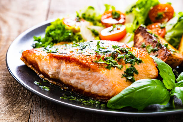 istock Fried salmon, fried potatoes and vegetables on wooden background 1217565035