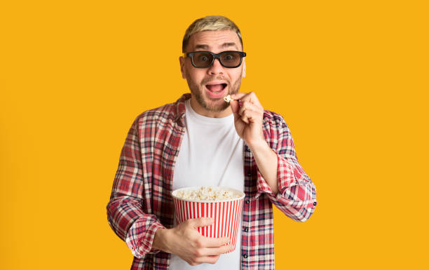 istock Man at cinema fun. Young male eats popcorn 1217565462
