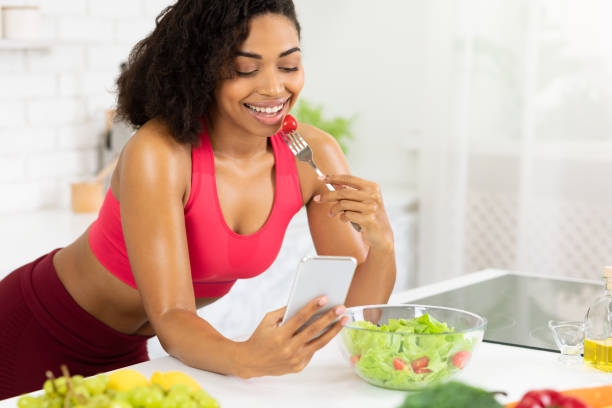 istock Black girl using smartphone and eating salad 1217566688