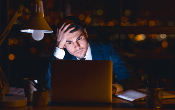 istock Entrepreneur At Laptop Thinking Touching Head Sitting Overnight In Office 1217567948