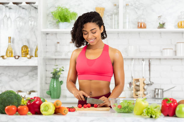 istock Beautiful young afro woman preparing vegetable salad 1217568051