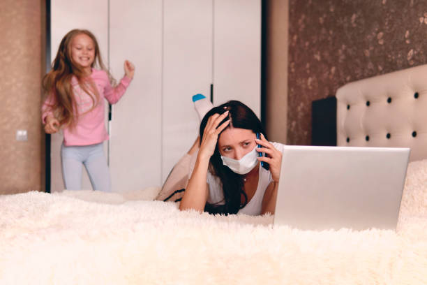 istock Children make it difficult to focus on work. mother in protective mask working from home during quarantine time at coronavirus. Child at home, kindergarden is closed. sick woman works under quarantine 1217568103