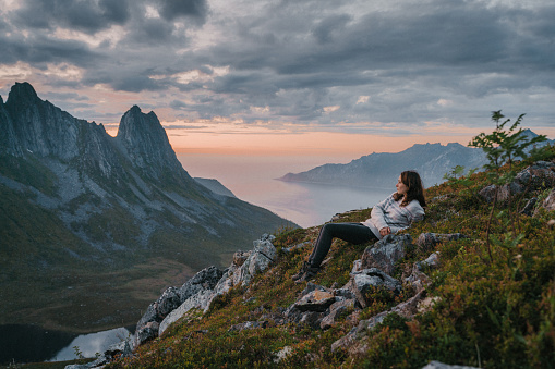 Young Caucasian woman  laying on the ground  and looking at scenic view of Senja