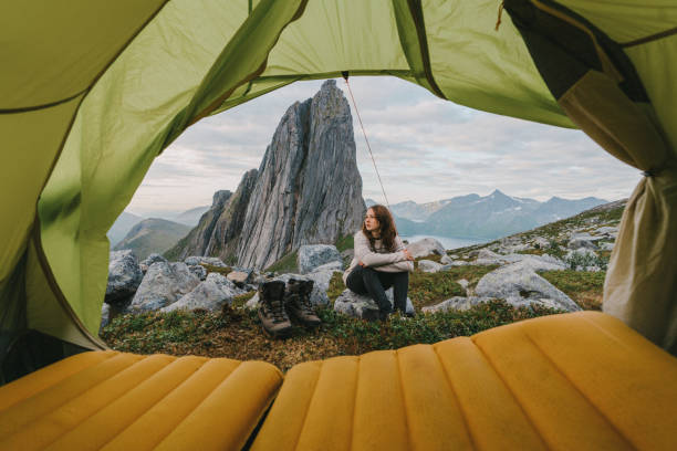 femme s’asseyant à l’extérieur de la tente dans l’île de senja dans des montagnes - bâtiment vu de lextérieur photos et images de collection