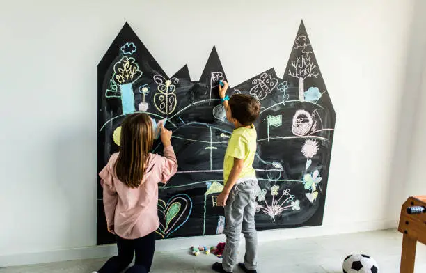 Brother and sister drawing on the blackboard in their room Stock photo